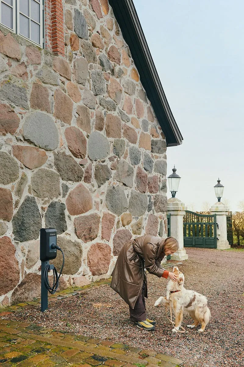 Kvinde er på en gård med sin hund, hvor der er Clever ladestander